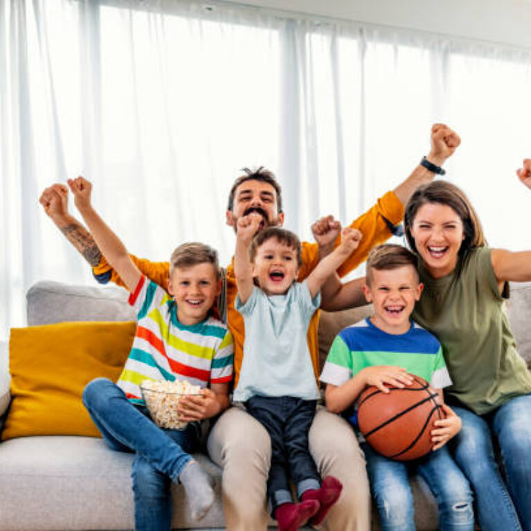 Excited, happy big family watching basketball match on the couch at home. Fans emotional cheering for favourite national team. Sport, TV, championship.