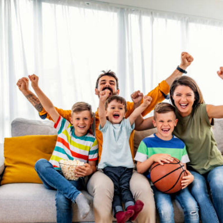 istockphoto-1225999103-612×612 Excited, happy big family watching basketball match on the couch at home. Fans emotional cheering for favourite national team. Sport, TV, championship.